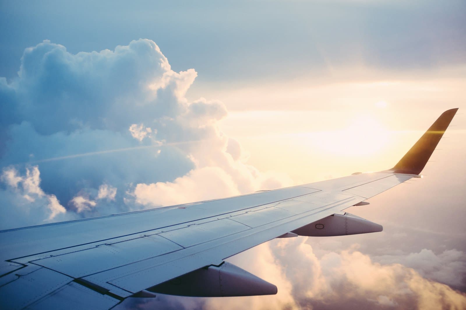 View over an aircraft wing above the clouds at sunrise