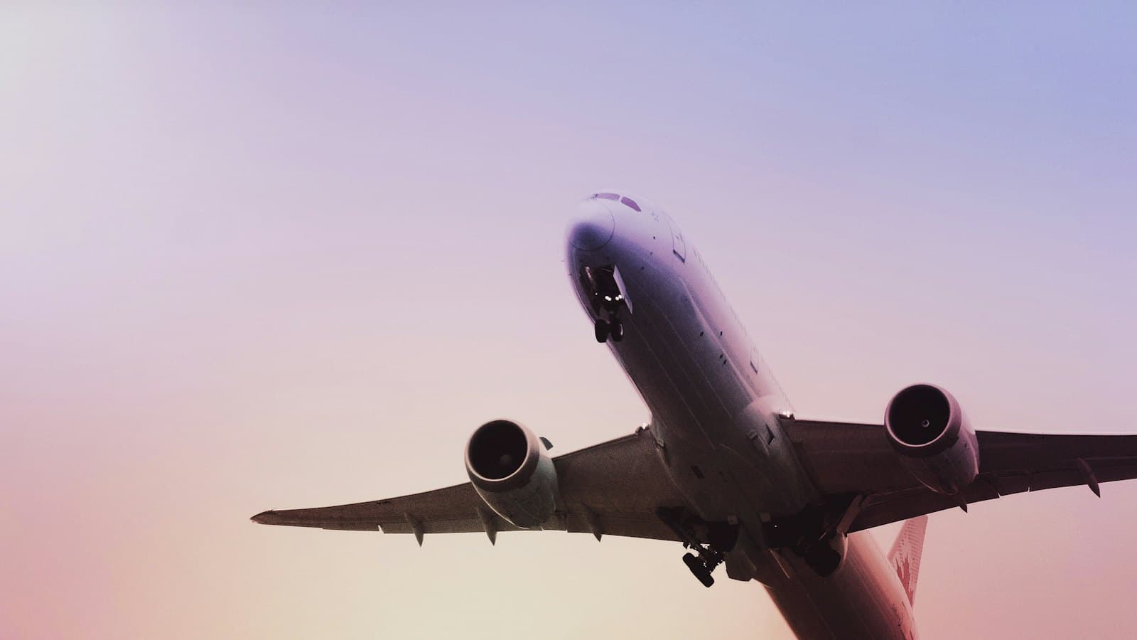 A passenger plane taking off into a pink evening sky